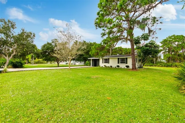a view of house with outdoor space and trees in the background