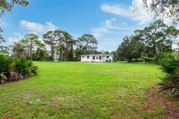 a view of a house with a big yard and large trees