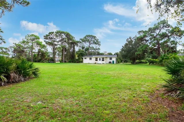 a view of a house with a big yard and large trees