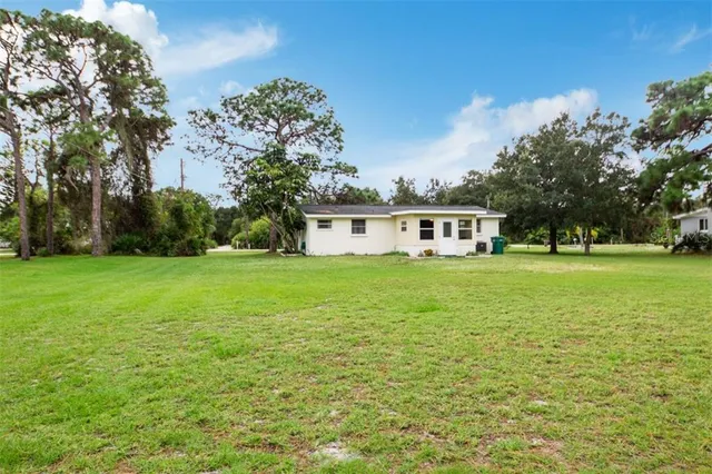 a white house that has a big yard with trees in the background