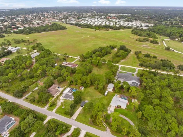 an aerial view of residential houses with outdoor space and trees