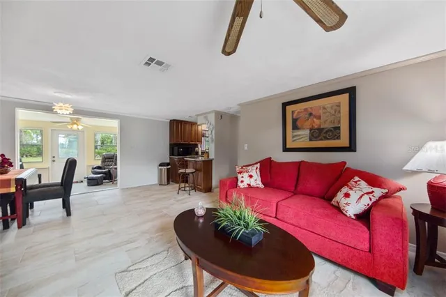 a living room with furniture kitchen view and a wooden floor