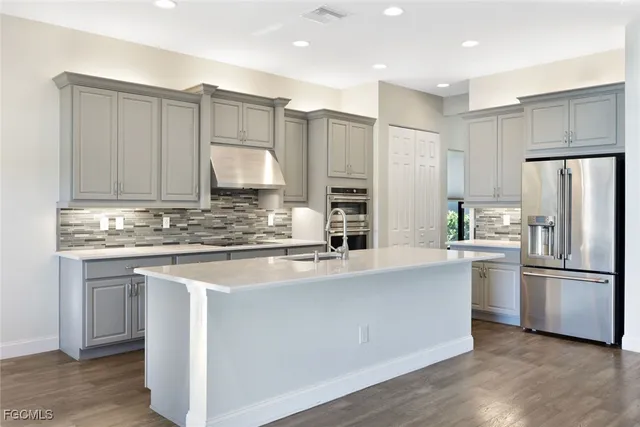 a kitchen with stainless steel appliances granite countertop a refrigerator sink and white cabinets