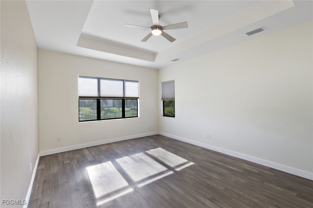 11727 Kati Falls Lane Fort Myers, FL 33913 - Photo 21 of 48 an empty room with wooden floor chandelier fan and windows