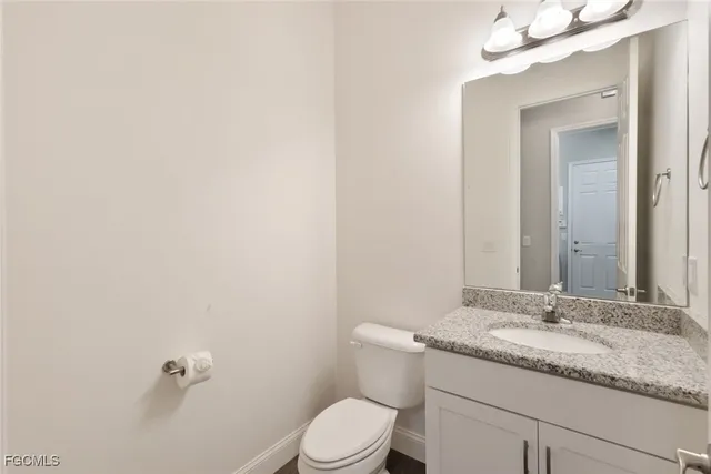 a bathroom with a granite countertop sink mirror vanity and toilet