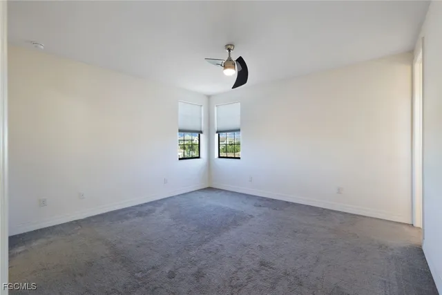 an empty room with windows and ceiling fan