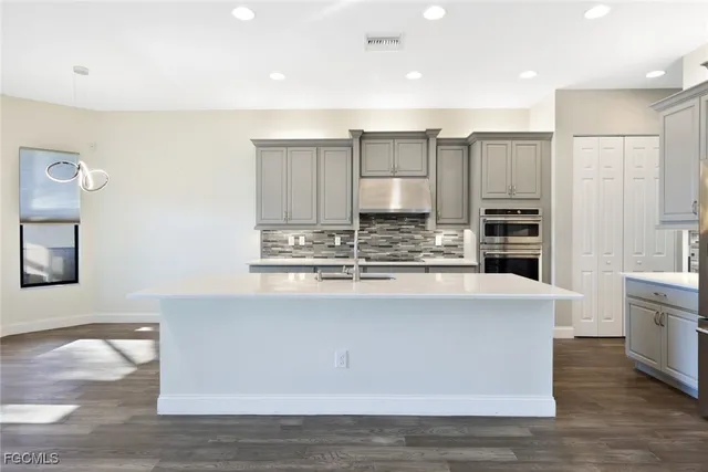 a large kitchen with stainless steel appliances a large counter top a stove and a refrigerator