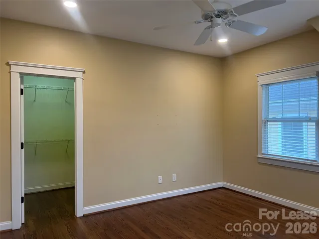 an empty room with wooden floor closet and windows