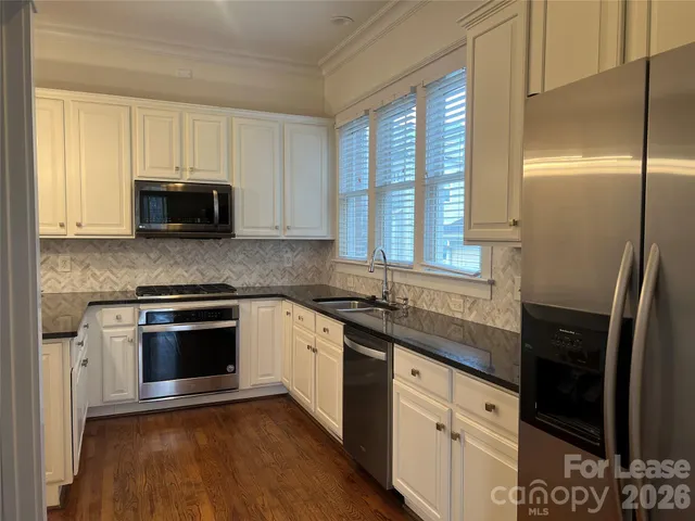a kitchen with granite countertop a stove a sink and a microwave