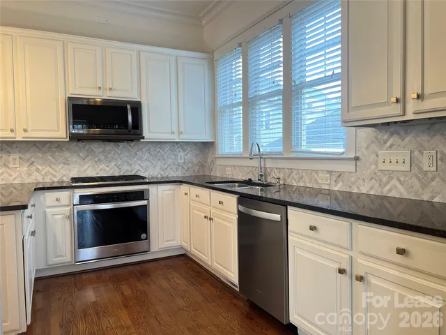 a kitchen with granite countertop white cabinets and a stove with wooden floor