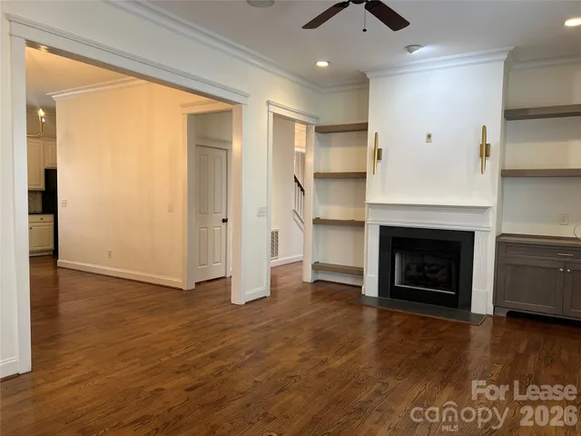 a view of an empty room with wooden floor and a fireplace