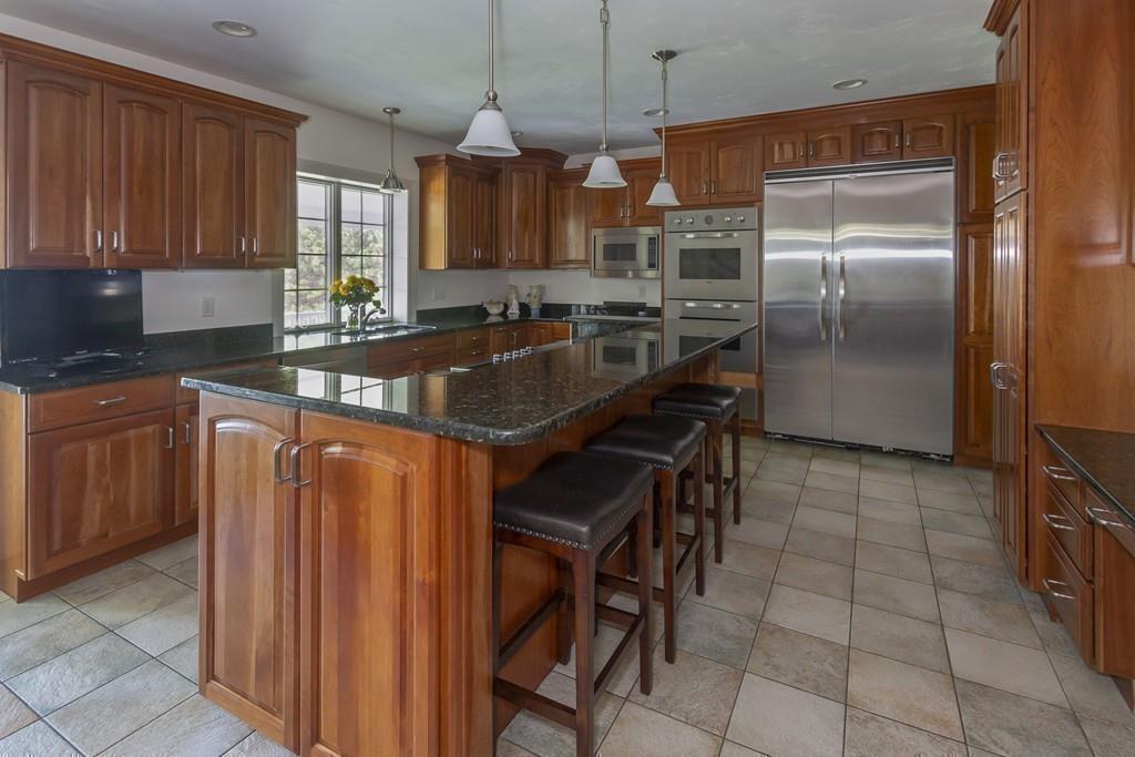 171 Great Neck Road Wareham, MA 02571 - Photo 9 of 26 a kitchen with kitchen island granite countertop wooden cabinets and a refrigerator