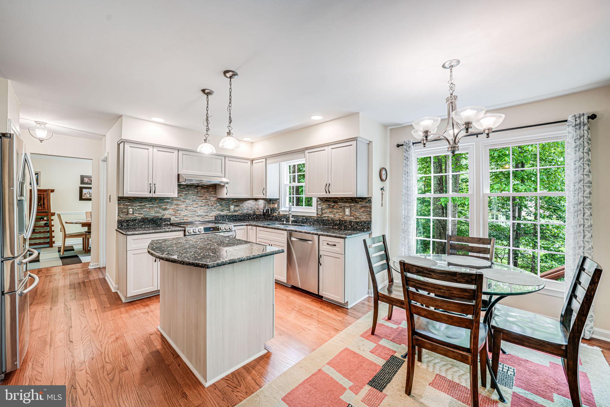 9802 Natick Road Burke, VA 22015 - Photo 12 of 45 a kitchen with kitchen island a large counter top space appliances and a chandelier