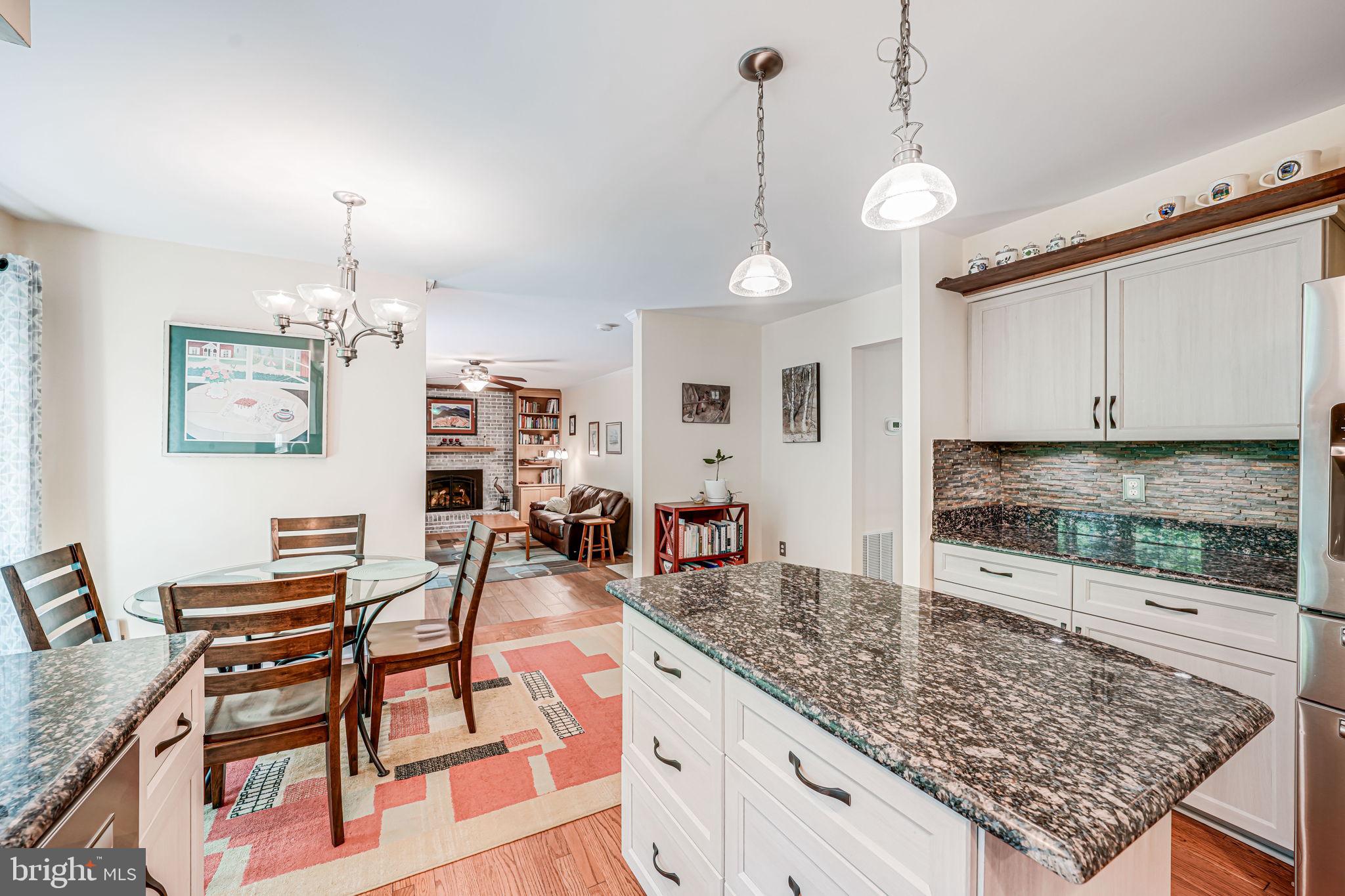 9802 Natick Road Burke, VA 22015 - Photo 13 of 45 a kitchen with stainless steel appliances granite countertop a stove top oven a sink a dining table and chairs with white cabinets