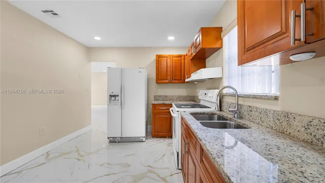 a kitchen with stainless steel appliances granite countertop a sink a stove and a refrigerator