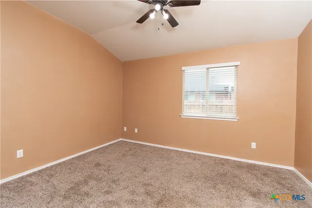 an empty room with a ceiling fan and window
