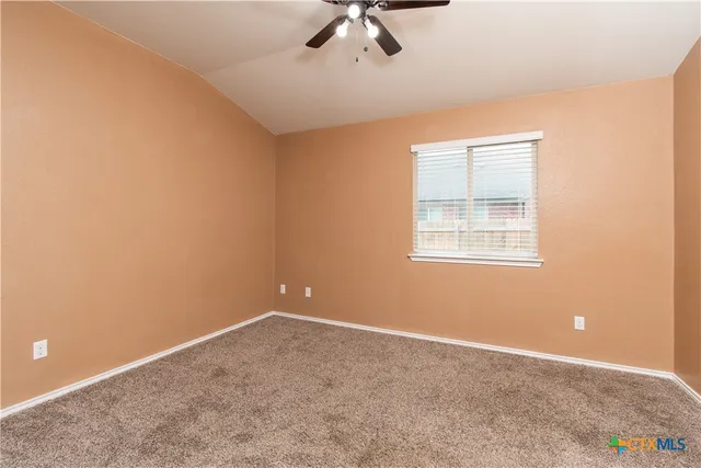 an empty room with a ceiling fan and window