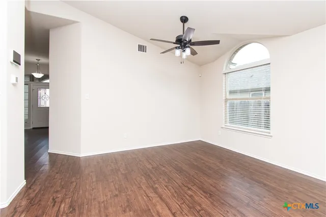 a view of empty room with wooden floor and fan