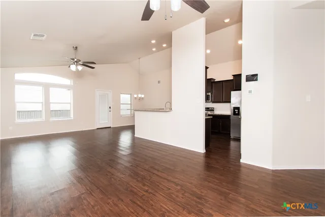an empty room with wooden floor and a kitchen