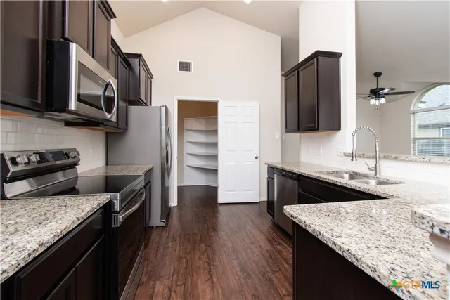 a kitchen with stainless steel appliances granite countertop a sink stove and refrigerator