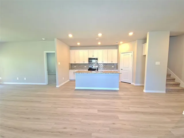 a view of kitchen with kitchen island wooden floor center island and stainless steel appliances