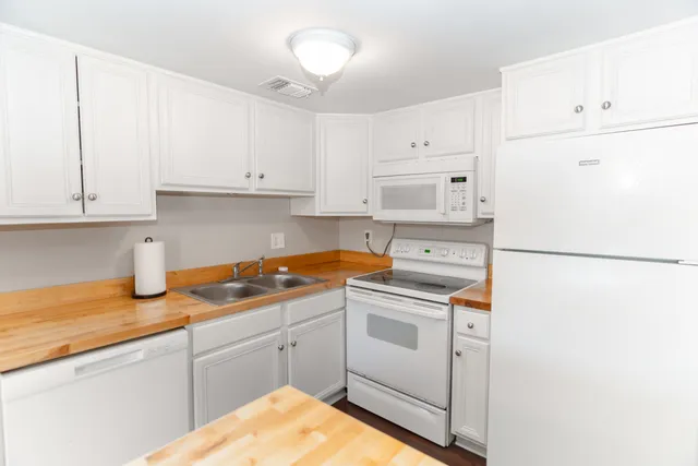 a kitchen with granite countertop white cabinets and white appliances