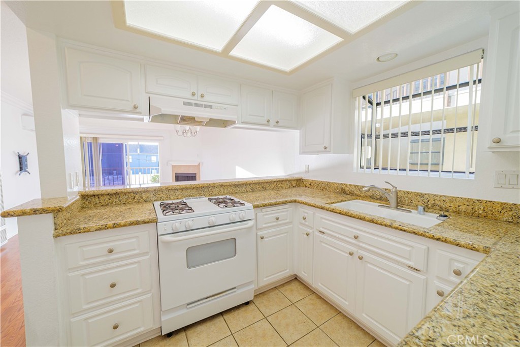 3516 East Ransom Street, Unit 204 Long Beach, CA 90804 - Photo 14 of 38 a kitchen with granite countertop white cabinets and white appliances