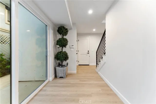 a view of a hallway with wooden floor and a potted plant