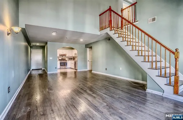 a view of a hallway with wooden floor staircase and a kitchen