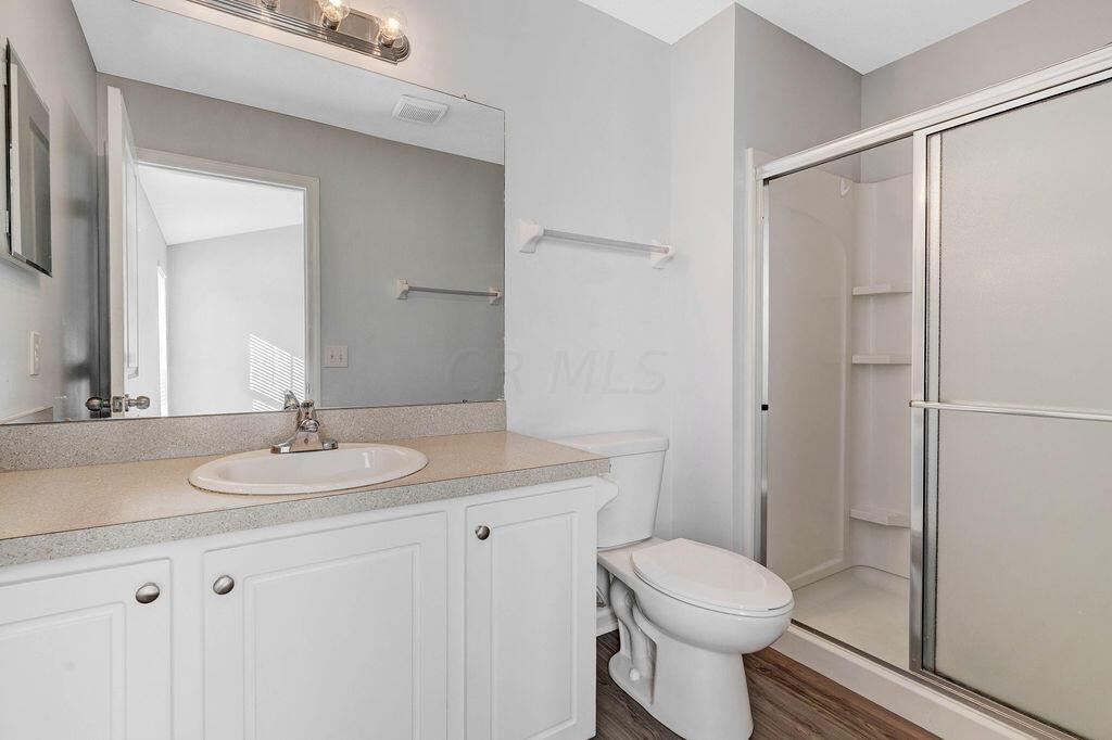 6345 Needletail Road, Unit 24634 Columbus, OH 43230 - Photo 20 of 58 • New luxury vinyl plank flooring ~ 2021 • Gray painted walls • Enclosed vanity with single bowl sinktop • Studio lighting strip • Mirrored medicine cabinet • Ceiling exhaust • Shower stall with glass door