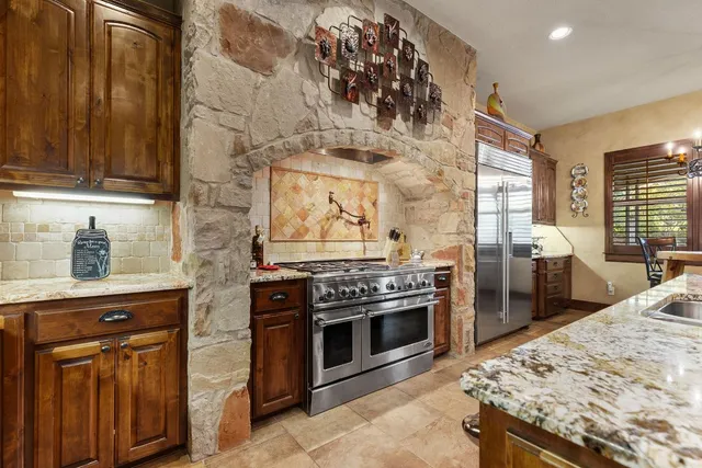 a kitchen with stainless steel appliances granite countertop a stove a sink and a microwave