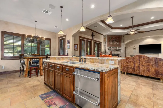 a large kitchen with a large counter top space a sink stainless steel appliances and cabinets