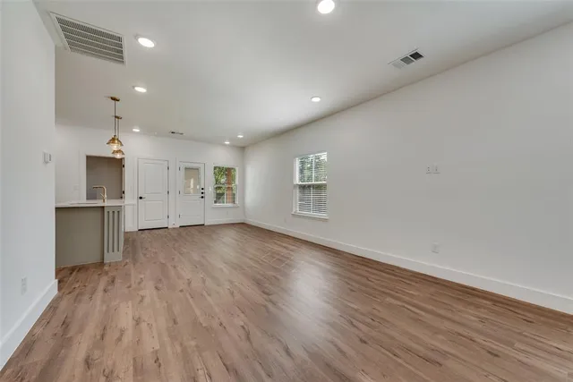 a view of an empty room with a window and wooden floor