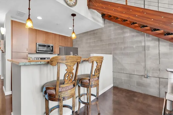 a kitchen with stainless steel appliances kitchen island granite countertop a table chairs in it and wooden floors