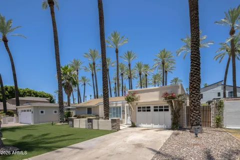 a front view of a house with a yard and palm trees