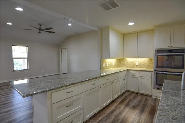 a kitchen with granite countertop cabinets stainless steel appliances a sink and wooden floor