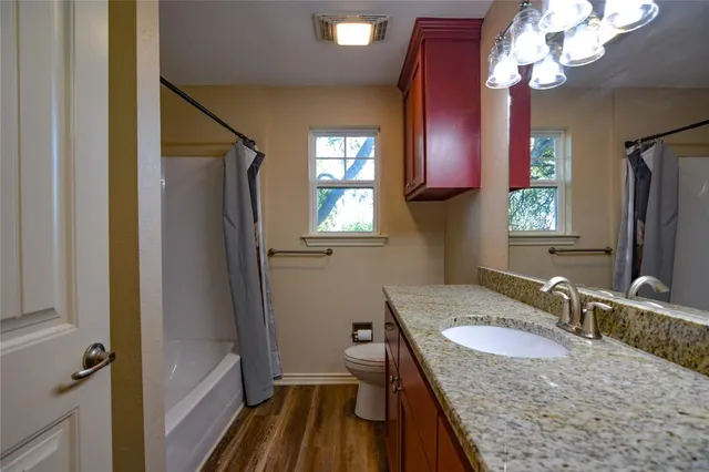 a bathroom with a granite countertop sink toilet a mirror and shower