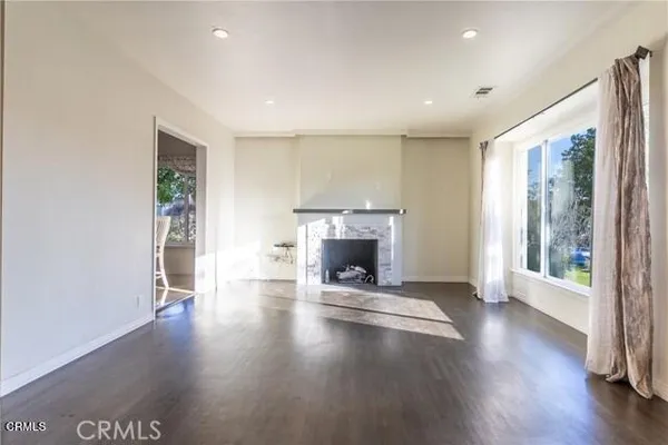 an empty room with wooden floor fireplace and windows