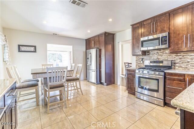 412 South Kenneth Road Burbank, CA 91501 - Photo 5 of 24 a kitchen with stainless steel appliances granite countertop a stove top oven a sink dishwasher a dining table and chairs with wooden floor