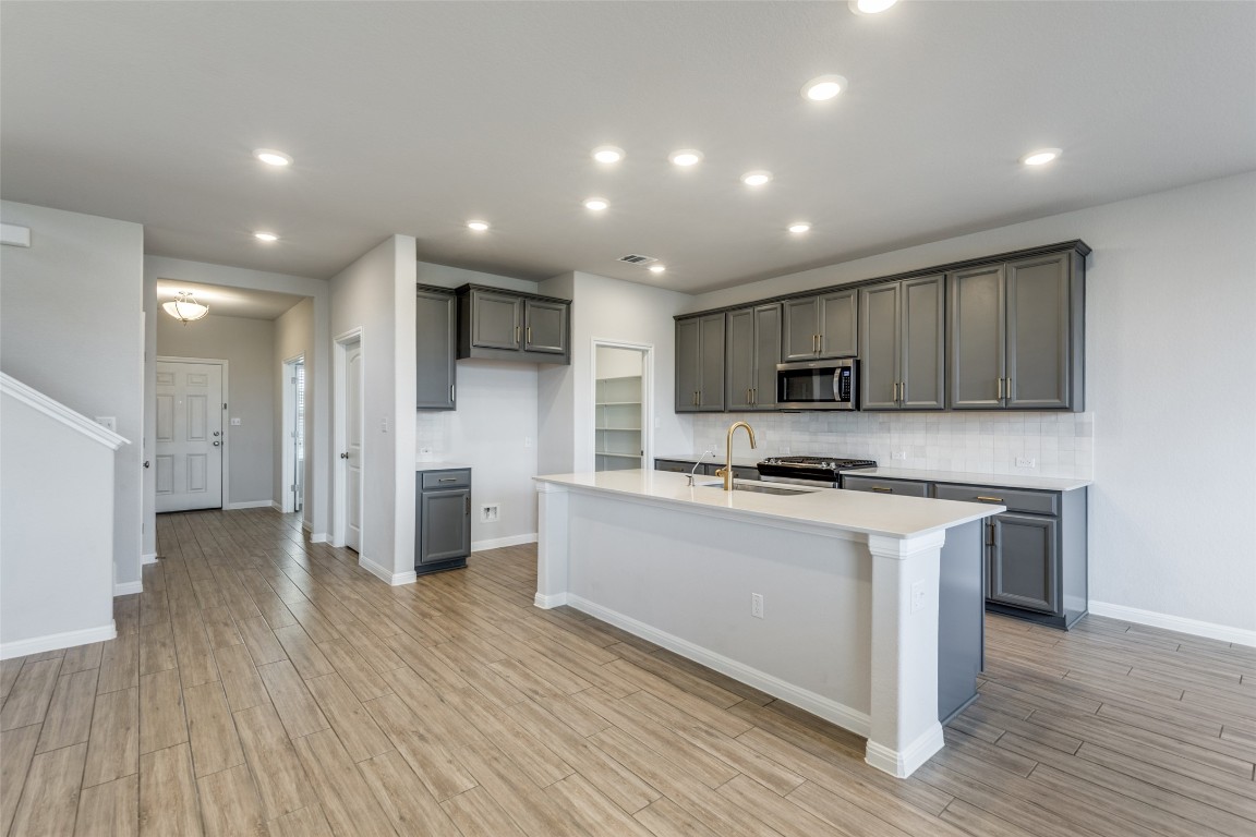 12912 Cerro Castellan Trace Manor, TX 78653 - Photo 2 of 36 a kitchen with stainless steel appliances granite countertop a stove top oven a sink and a refrigerator