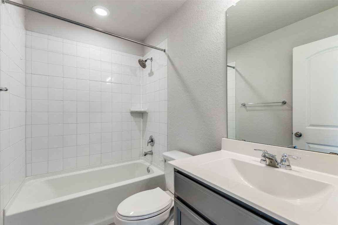 12912 Cerro Castellan Trace Manor, TX 78653 - Photo 23 of 36 a bathroom with a bathtub shower sink vanity mirror and toilet