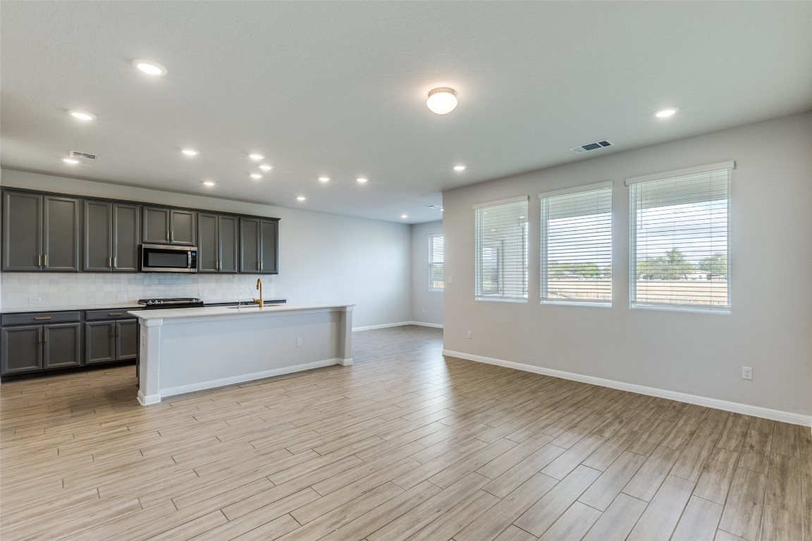12912 Cerro Castellan Trace Manor, TX 78653 - Photo 6 of 36 a large kitchen with a large counter top a sink stainless steel appliances and cabinets