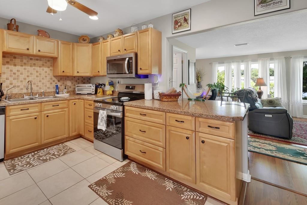 50 Bonita Road DeBary, FL 32713 - Photo 4 of 43 a kitchen with stainless steel appliances kitchen island granite countertop a sink dishwasher stove and white cabinets with wooden floor