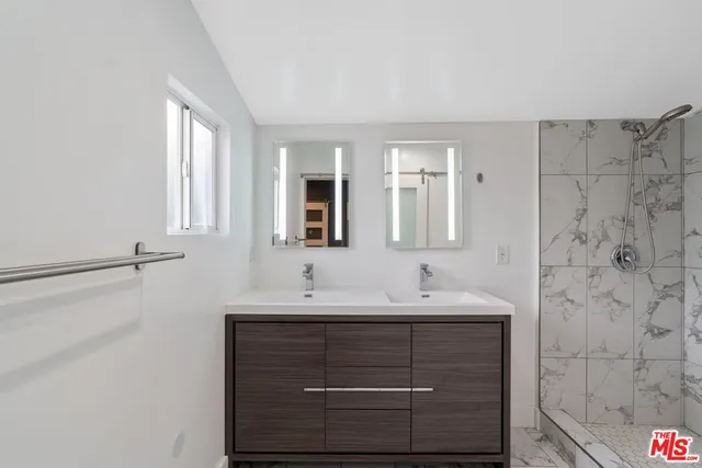 a bathroom with a double vanity sink mirror and shower