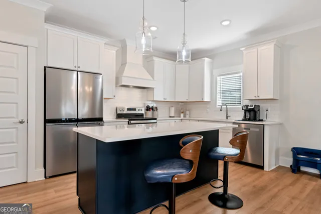 a kitchen with stainless steel appliances granite countertop a sink a stove a refrigerator and chairs