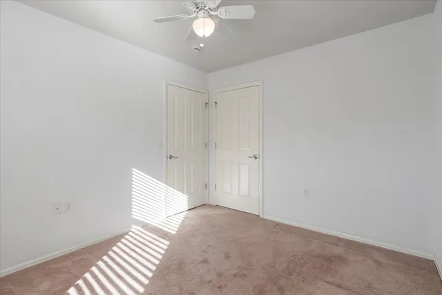 an empty room with windows and chandelier fan