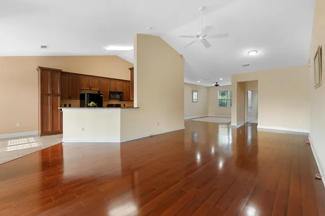 a view of a living room a kitchen with wooden floor and cabinets