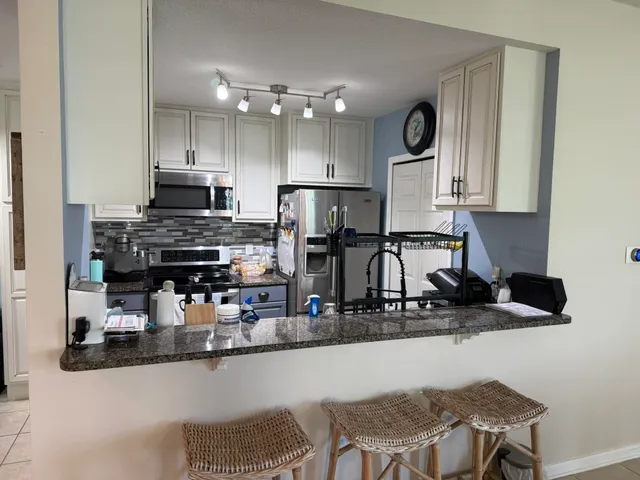 a kitchen with stainless steel appliances granite countertop a stove top oven a sink a dining table and chairs