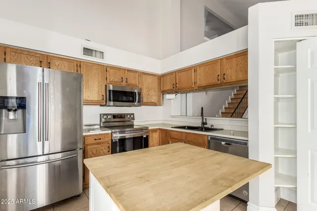 a kitchen with stainless steel appliances granite countertop a refrigerator a stove a sink dishwasher and white cabinets with wooden floor