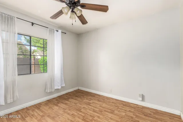 a view of empty room with wooden floor and fan
